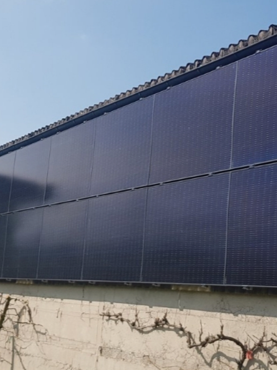 Solarmodule an einer Gebäudefassade mit Ziegeldach