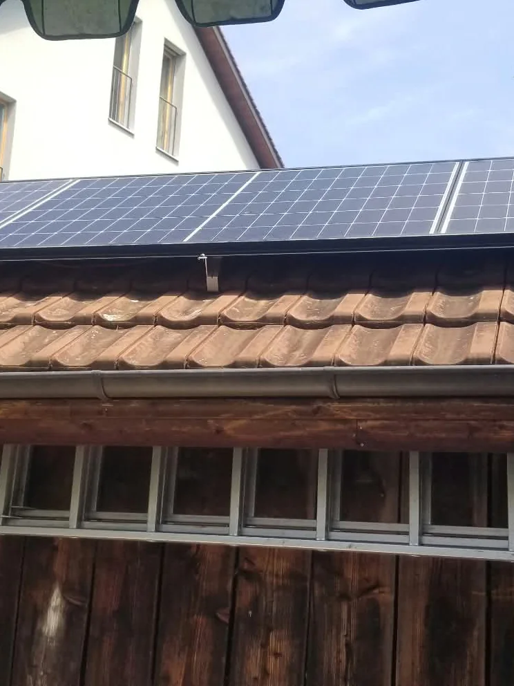 Solarmodule auf einem Ziegeldach über einer Holzterrasse