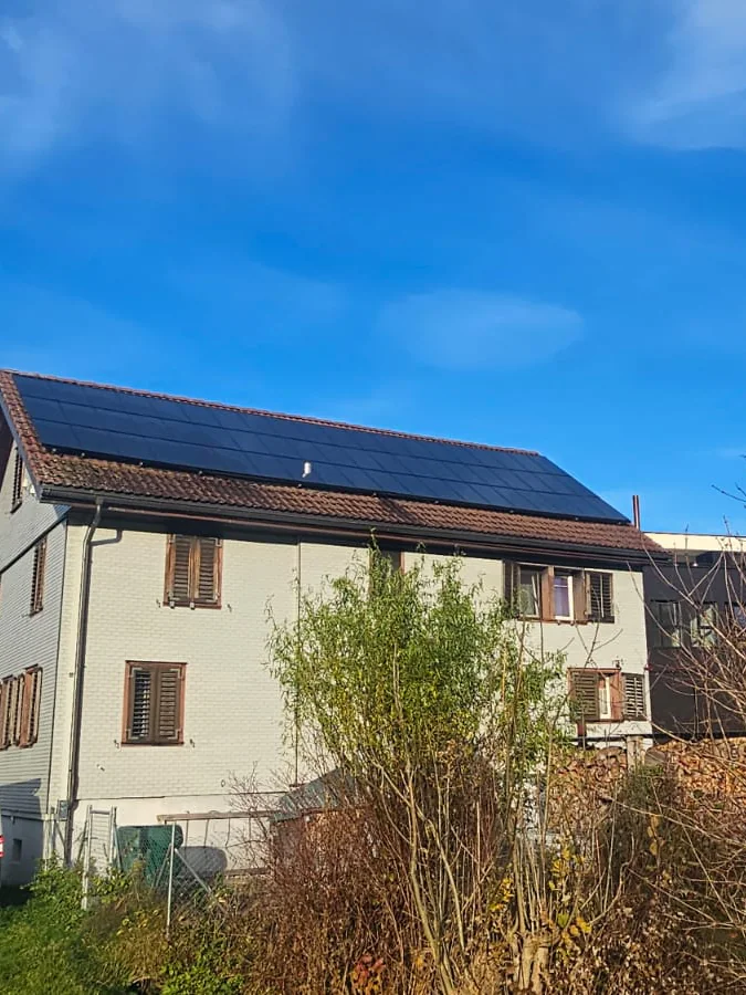 Wohnhaus mit Solaranlage auf dem Giebeldach vor blauem Himmel