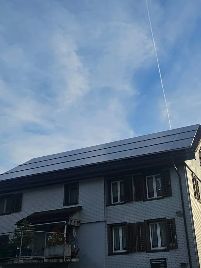 Solaranlage auf einem Wohnhaus vor einer Bergkulisse
