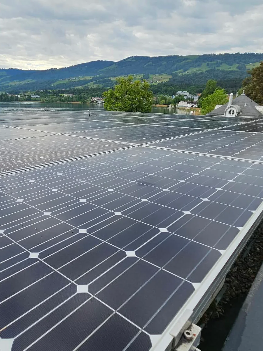 Solarmodule auf einem Flachdach mit Blick auf See und Berge
